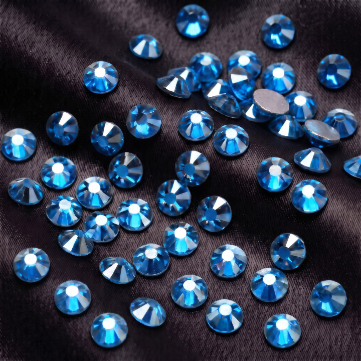 Lazurowe cyrkonie szklane Capri Blue Satin rozsypane na jasnej tkaninie