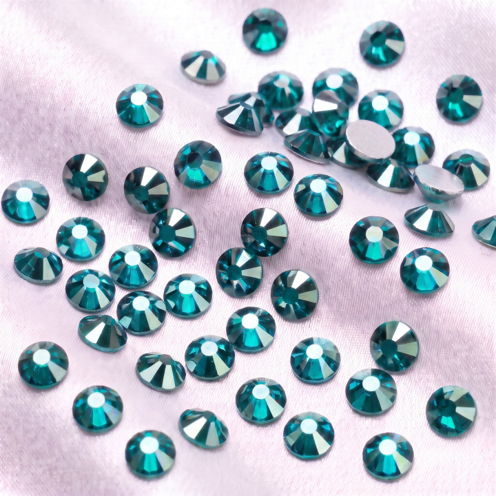 Turkusowe cyrkonie szklane Blue Zircon Satin rozsypane na jasnej tkaninie