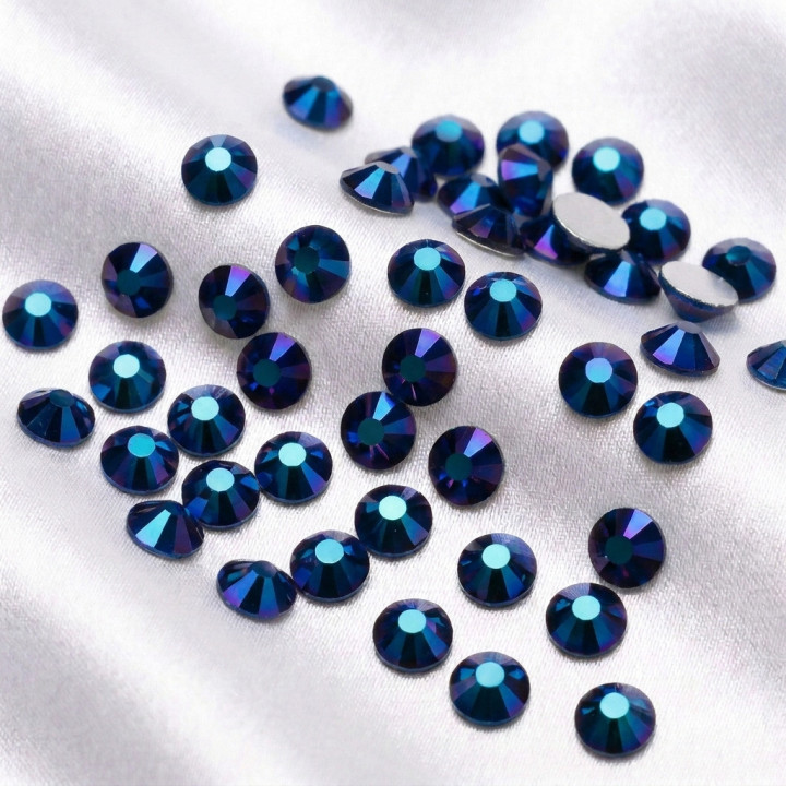 Granatowe cyrkonie szklane Metallic Blue rozsypane na jasnej tkaninie