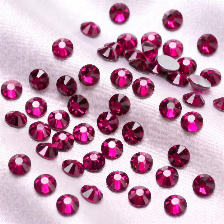Fuksjowe cyrkonie szklane Hot Pink rozsypane na jasnej tkaninie