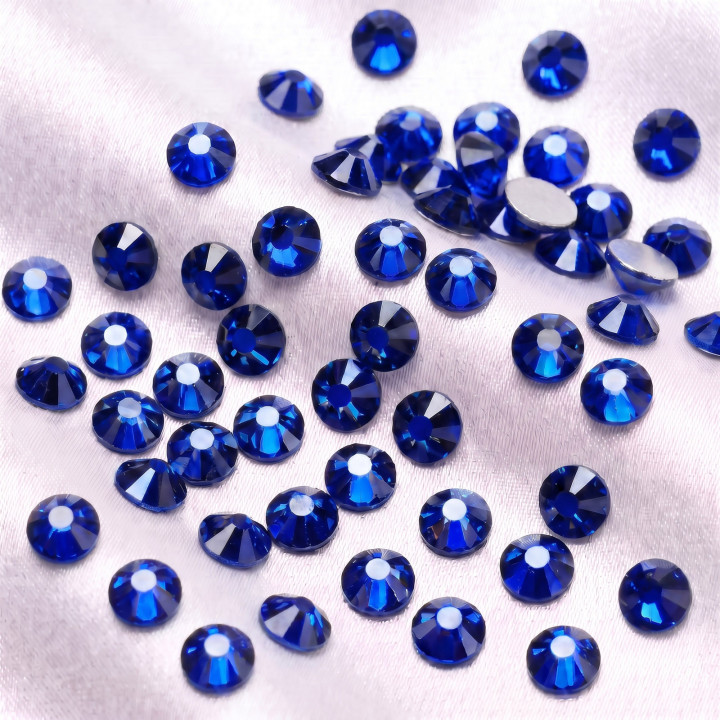 Szafirowe cyrkonie szklane Sapphire rozsypane na jasnej tkaninie
