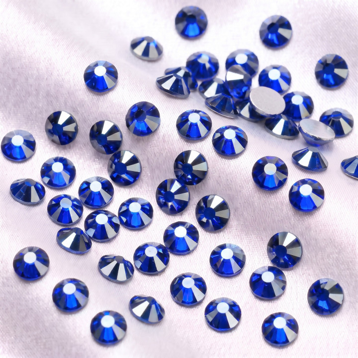 Niebieskie cyrkonie szklane Sapphire Satin rozsypane na jasnej tkaninie